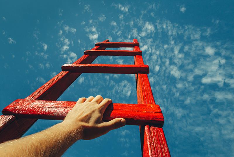 Hand Reaching For Red Ladder Leading To A Blue Sky