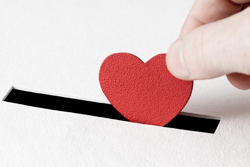 Hand Putting Red Paper Heart Into White Box Slot