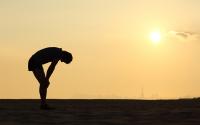 Silouette of a man bent over and catching his breath