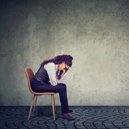 Woman feeling stress from work sitting on chair and looking down