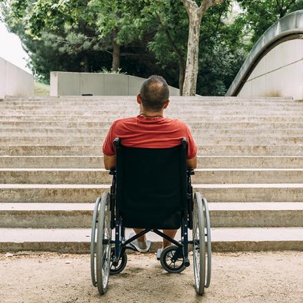 person in wheelchair stopped in front of stairs