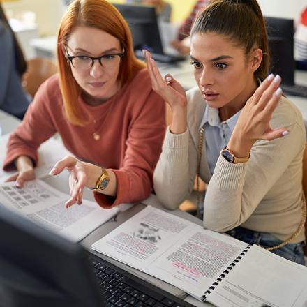 A female student giving help to a colleague at the informatics lecture.