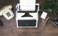 Phone, typewriter and office supplies on a wooden desk